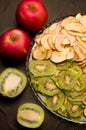 fruit chips apple, kiwi, on a platter on a black background next to fresh fruit. Royalty Free Stock Photo