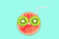 Fruit creative face with slices of grapefruit and kiwi, drinking straw on blue background, fruit juice concept Royalty Free Stock Photo