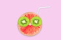 Fruit creative face with slices of grapefruit and kiwi, drinking straw on pink background, juice and summer concept Royalty Free Stock Photo