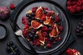 Fruit fig, grape, raspberry and pomegranate salad on black plate