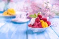 Fruit ice cream with raspberries and mango. Flowers and ripe mango on a blue wooden background. Breakfast is sweet and coffee. Royalty Free Stock Photo