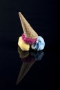 Fruit ice cream scoops overhead on a cornet, served with several colorful spoons isolated on black background