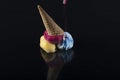 Fruit ice cream scoops overhead on a cornet, served with several colorful spoons isolated on black background