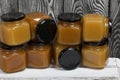 Fruit jam in jars. Stands on a white-painted wooden box. Against the background of black pine boards