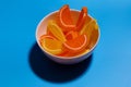 Fruit jelly marmalade slices of lemon and orange in white bowl on blue background Royalty Free Stock Photo