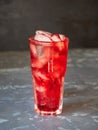 Fruit lemonade with cherry and ice cubes in a tall glass