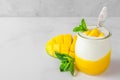 Fruit mango yogurt with fresh mint in a glass with a spoon over concrete background. healthy breakfast Royalty Free Stock Photo