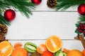 Fruit orange, tangerine and kiwifruit. Branch christmas tree and red ball with cone and cinnamon sticks on white wooden vintage ba Royalty Free Stock Photo