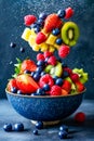 Fruit pieces are being flung out of bowl creating messy scene with strawberries kiwi and other fruits scattered around