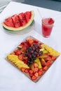 Fruit plate with watermelon, pear, grapes, strawberries, pineapple and fresh juice.