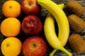 Fruit platter of fresh mandarins, kiwi, red apples and bananas on gray wooden table