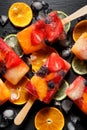 Fruit popsicles, homemade fruit ice lolly of various fruits with the addition of citrus lemonade on a black background, top view.