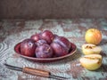Fruit preparation for pie or jam. Red plums on a flat plate, whole apple and cut into halves