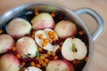 Fruit punch with sliced half apples and buckthorn berries in metal cooking pot macro