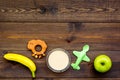 Fruit puree for baby. Jar with food, apple, banana, toys on dark wooden background top view copy space Royalty Free Stock Photo