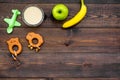 Fruit puree for baby. Jar with food, apple, banana, toys on dark wooden background top view copy space Royalty Free Stock Photo