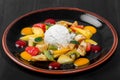 Fruit salad with banana, kiwi, orange, grapefruit in pineapple on plate over dark background. Healthy breakfast Royalty Free Stock Photo