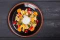 Fruit salad with banana, kiwi, orange, grapefruit in pineapple on plate over dark background. Healthy breakfast Royalty Free Stock Photo