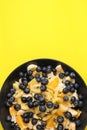 Fruit salad with blueberries, banana, orange, apple and kiwi on a black plate isolated on a yellow background. Vitamin cocktail. Royalty Free Stock Photo