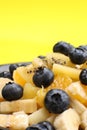 Fruit salad with blueberries, banana, orange, apple and kiwi on a black plate isolated on a yellow background. Vitamin cocktail. Royalty Free Stock Photo