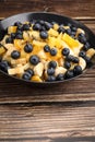 Fruit salad with blueberries, banana, orange, apple and kiwi on a black plate and wooden table. Vitamin cocktail. Royalty Free Stock Photo