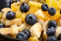 Fruit salad with blueberries, banana, orange, apple and kiwi on a black plate and wooden table. Vitamin cocktail. Royalty Free Stock Photo