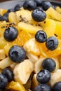 Fruit salad with blueberries, banana, orange, apple and kiwi on a black plate and wooden table. Vitamin cocktail. Royalty Free Stock Photo