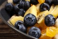 Fruit salad with blueberries, banana, orange, apple and kiwi on a black plate and wooden table. Vitamin cocktail. Royalty Free Stock Photo