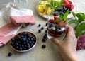 Fruit salad and natural greek yogurt with fresh berries. Hand holding glass with yogurt and fruits Royalty Free Stock Photo