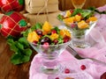 Fruit salad with orange pieces, cranberries, date fruits and arugula in a glass salad bowl