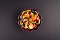 Fruit Salad in purple Bowl on Black Table, Top View. centered