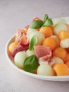 fruit salad with two varieties and colors of melon balls, serrano ham and fresh basil leaves. Royalty Free Stock Photo