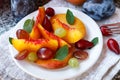 Fruit salad in white plate. Snack of fresh peaches, grapes, dogwood, plums, and mint leaves. Healthy Breakfast Royalty Free Stock Photo