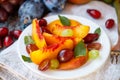 Fruit salad in white plate. Snack of fresh peaches, grapes, dogwood, plums, and mint leaves. Healthy Breakfast Royalty Free Stock Photo