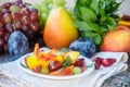 Fruit salad in white plate. Snack of fresh peaches, grapes, dogwood, plums, and mint leaves. Healthy Breakfast Royalty Free Stock Photo