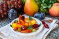 Fruit salad in white plate. Snack of fresh peaches, grapes, dogwood, plums, and mint leaves. Healthy Breakfast Royalty Free Stock Photo