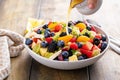Fruit salad on a wooden table with berries and honey dressing