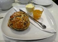 Fruit scone with jam and cream on a plate