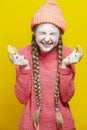 Fruit Series. Winsome Girl In Coral Knitted Clothing Biting Acid Yellow Lemon Slices In Front of Face Over Yellow Background