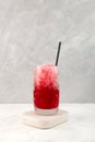 Fruit Shaved ice with natural juice. Red Slushie drink on grey background. Summer Granizado drink