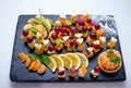 Fruit skewers - fresh apple, kiwi, lemon slices, tangerine, grapes and cheese, served on black stone tray Royalty Free Stock Photo