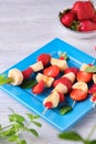 Fruit skewers with strawberry and banana on a blue square plate on a light wooden background. Dishes party, children, holiday Royalty Free Stock Photo