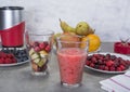 Fruit smoothies with blueberries, raspberries, apple, orange , pear and banana on gray background.