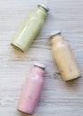 Fruit smoothies of different colors in glass bottles on white wooden surface. Top view, from above Royalty Free Stock Photo