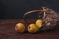 Fruit still life. Three yellow pears and a basket on a wooden table Royalty Free Stock Photo