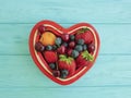 fruit strawberry, blueberry, cherry, apricot plate heart on blue wooden Royalty Free Stock Photo