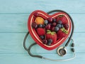 Fruit strawberry, blueberry, cherry, apricot plate heart on blue wooden stethoscope sweet antioxidant mixed Royalty Free Stock Photo