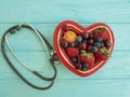 Fruit strawberry, blueberry, cherry, apricot plate idea heart on blue wooden stethoscope sweet antioxidant mixed Royalty Free Stock Photo