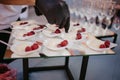 Fruit tart with raspberries and cream, cakes and sweetness on wedding. Hand putting berries in dessert. Wedding catering food.