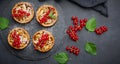 Fruit tart with red currants sprinkled with powdered sugar on a black table, delicious dessert Royalty Free Stock Photo